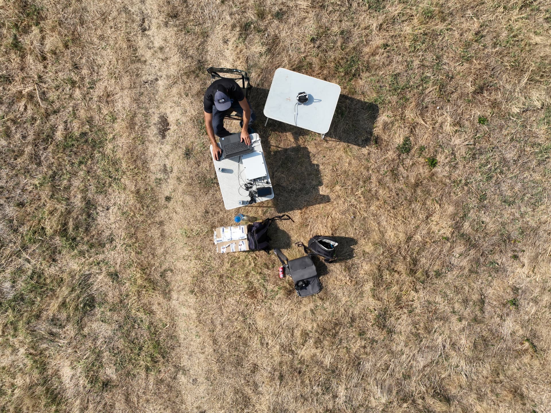 Overhead view of a Tersonic operator working at a laptop and test table in a dry outdoor field
